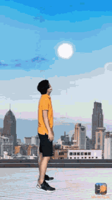 a man in a yellow shirt stands on a roof looking up at the sun