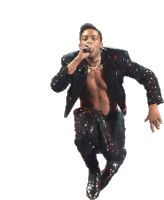 a shirtless man in a sequined suit is jumping in the air while singing into a microphone