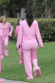 a woman in a pink pajama set is walking down the sidewalk