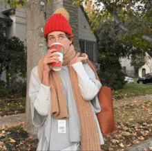 a person wearing a red hat and scarf is drinking from a cup that says ' xmas ' on it