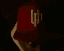 a man wearing a red hat and a white hoodie is looking at the camera in the dark .