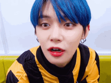 a young man with blue hair and red lipstick is wearing a yellow and black striped shirt