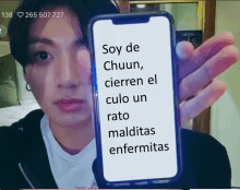 a man is holding a cell phone with the words soy de chuun written on it