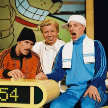 three men are sitting next to each other in front of a clock that says 3:41 .