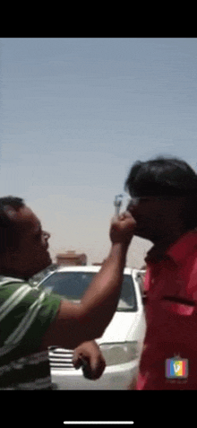 two men are having a fight in front of a white car