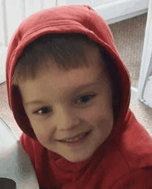 a young boy wearing a red hoodie is smiling