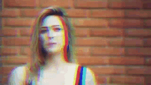 a woman with rainbow hair is standing in front of a brick wall ..