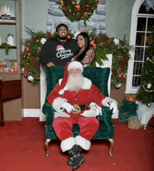 a man in a merry christmas shirt stands behind santa