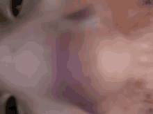 a blurred image of a person 's face with a purple spot on it .