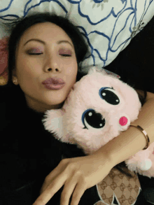 a woman laying on a bed with her eyes closed and a pink stuffed animal