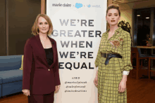 two women standing next to a sign that says we 're greater when we 're equal