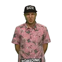 a man wearing a pink shirt and a black sox hat