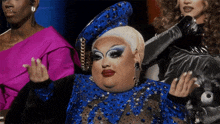 a drag queen wearing a blue dress and a hat