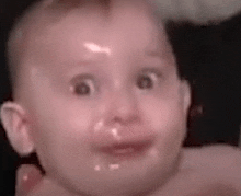 a close up of a baby 's face with a surprised look on its face .