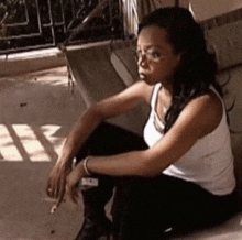 a woman is smoking a cigarette while sitting on the ground .