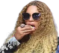 a woman with long curly hair wearing sunglasses and a ring is eating a sandwich .