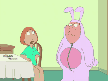 a woman sits at a table next to a man in a pink bunny costume