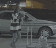 a woman in a striped shirt is standing in front of a car