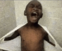 a young boy is taking a shower with a towel over his shoulders .