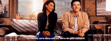 a man and a woman are sitting on a couch holding hands and smiling .