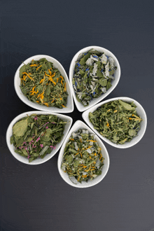 four bowls filled with different types of dried herbs are arranged in a circle