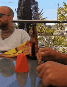 a man sitting at a table with a bottle of beer and a cup that says ' coca cola ' on it