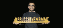 a man wearing glasses is holding a sign that says #arbucchinemamma