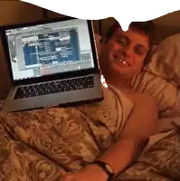 a man laying in bed with a laptop on his lap that says ' adobe ' on the screen