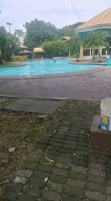 a person is swimming in a swimming pool surrounded by a brick walkway