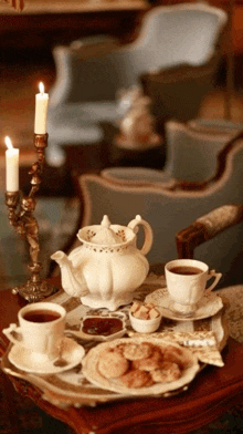 a table with a teapot cups and cookies and candles