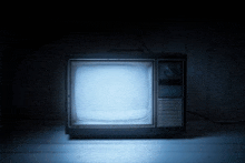 an old television is lit up in the dark with a blue screen