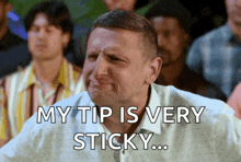 a man is sitting in a crowd with a caption that says my tip is very sticky