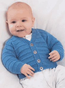 a baby is wearing a blue knitted cardigan .