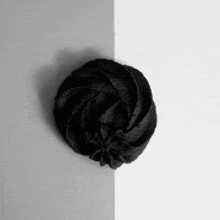 a black flower is on the corner of a white wall