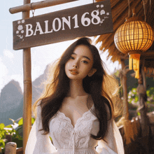 a woman in a white dress is standing in front of a sign that says balon168