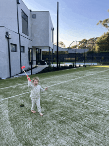 a little boy is playing on a tennis court with a pink stick