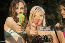 three young girls in bikinis are holding water guns in their hands