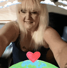 a woman is taking a selfie with a heart on top of a green globe