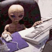 an alien is sitting at a desk typing on a keyboard .