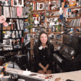 a woman in a black dress sits in front of a piano in a room filled with lots of toys