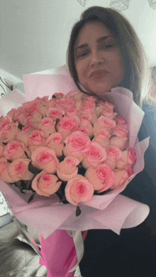 a woman holding a bouquet of pink roses