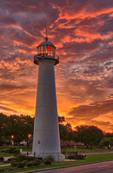 a lighthouse with a sunset in the background and a flag on top