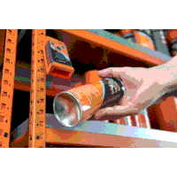 a person is holding a can in their hand in front of a shelf .