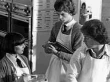 a man is holding a clipboard while two women look on