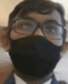 a man wearing glasses and a mask is taking a selfie .