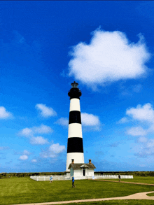 a black and white lighthouse with a blue sky and white clouds in the background