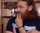 a man with long hair and a beard is eating a piece of food while sitting in front of a boxing ring .