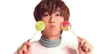 a young man is holding two lollipops in front of his mouth