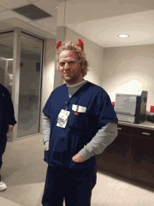 a man wearing scrubs and devil horns has a name tag that says ' a.j. ' on it