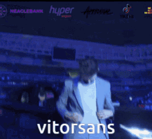 a man in a suit is standing in front of a car and the word vitorsans is on the screen